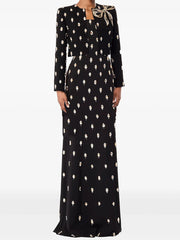 Model wearing a maxi dress with an all-over embellished motif and a cropped blazer, styled as a coordinated formal set on a studio background.