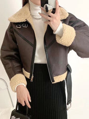 A woman is watching a smartphone while wearing a faux fur-lined women's jacket with a belt.
