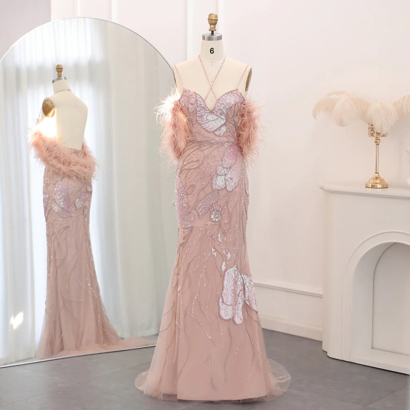 Pink evening gown with feather details on a mannequin against a white background