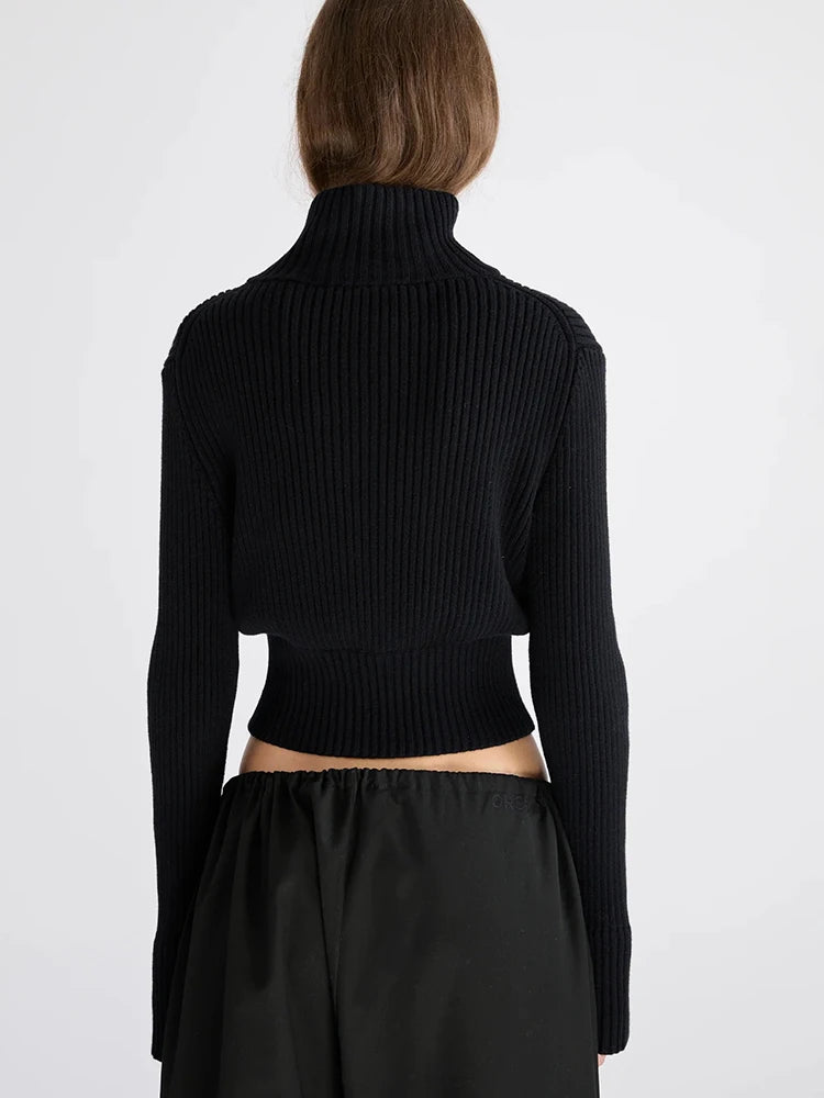 Black zip-up ribbed knit cardigan styled with relaxed trousers.