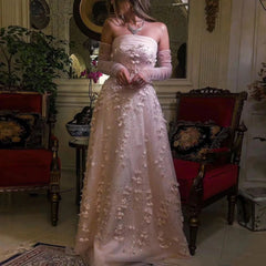 A woman in a pink floral dress is standing in an elegant room with red chairs and decorative elements.