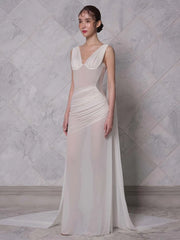 Floor-length sleeveless evening gown in white with sculpted panels. A woman wearing a long, elegant dress against a marble wall. 