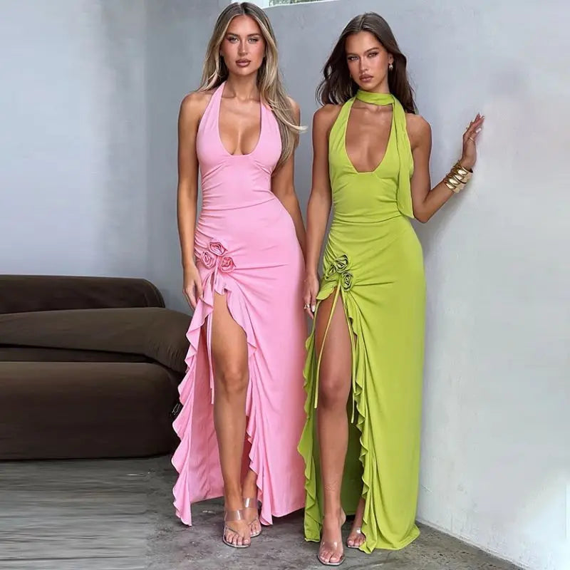 This image features two women showcasing stylish, long dresses in vibrant pink and bright green colors. Both dresses are designed with a floral applique at the halter neck and a split that enhances their flowing silhouette.