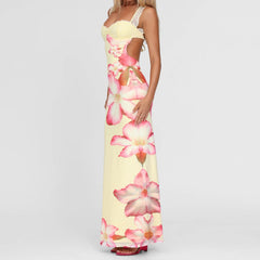 A woman modeling a floral backless cami maxi dress with a tie-back detail.