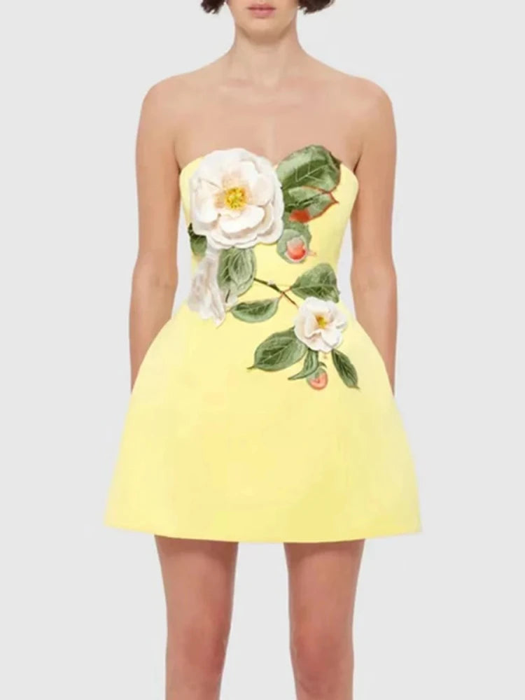 A woman wearing a yellow embroidered floral detailing on a yellow mini dress on a plain background.
