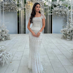 A woman wearing an elegant floral mermaid gown with a matching jacket for a formal event.