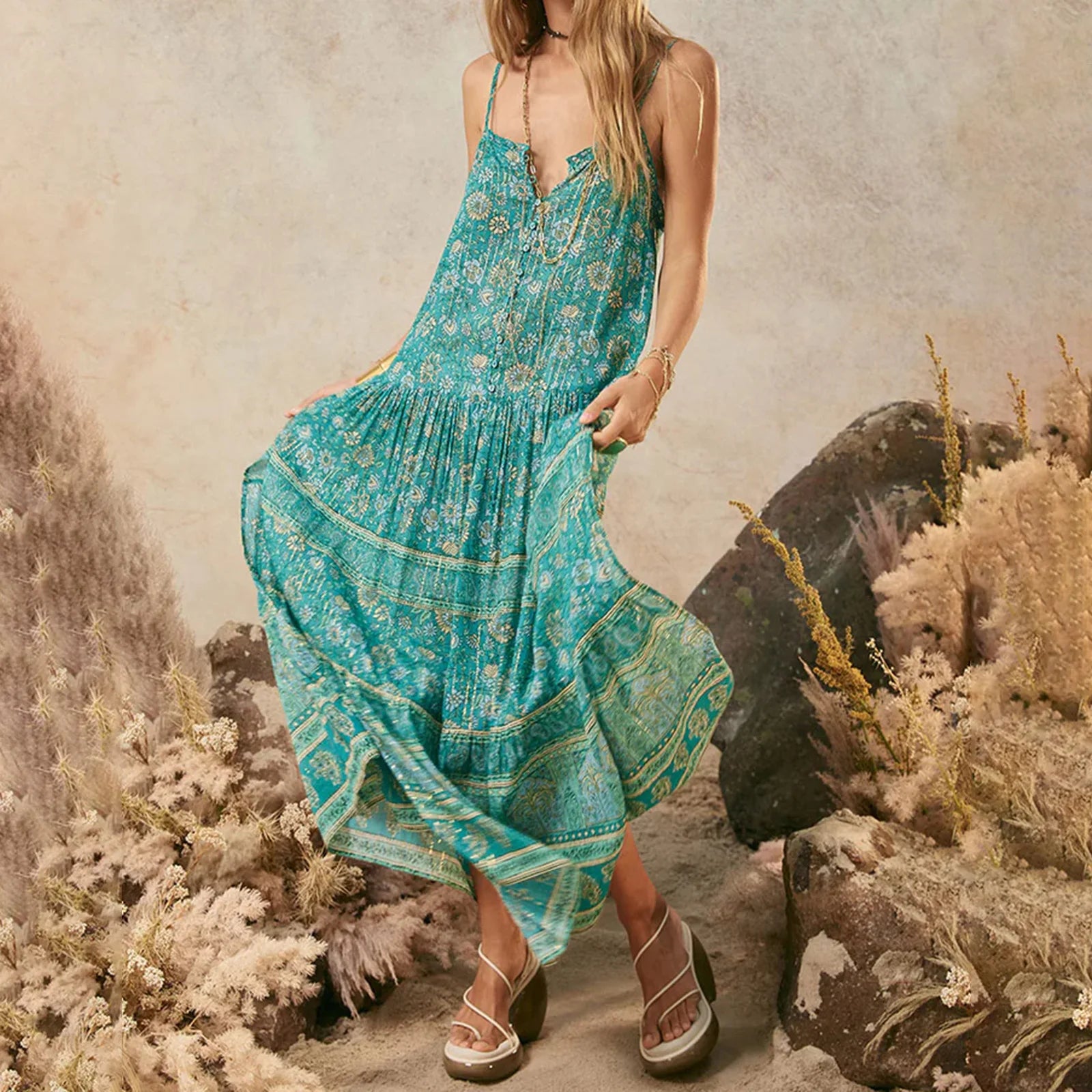 A woman modeling a floral print bohemian maxi dress with spaghetti straps.