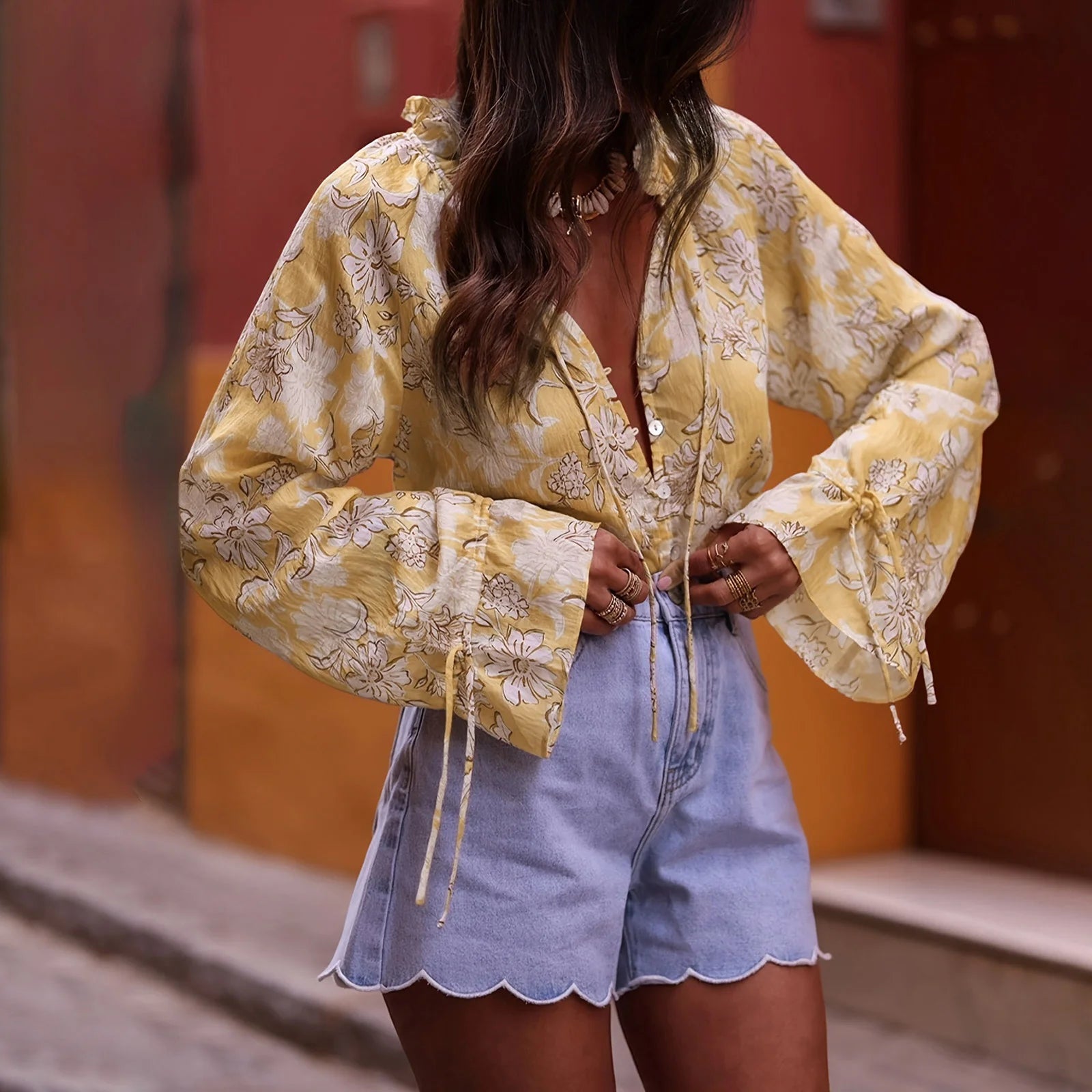 A woman modeling a floral print V-neck blouse with long flare sleeves.