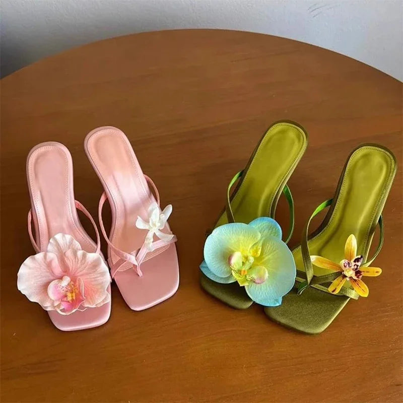 Pink and green sandals with floral decorations on a wooden surface