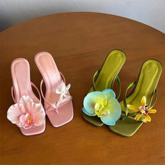 Pink and green sandals with floral decorations on a wooden surface