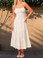 A woman modeling a floral smocked midi dress for a summer day out.