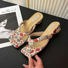 Floral wedge clip toe slides for women, styled for summer beach wear on a black surface with a magazine in the background