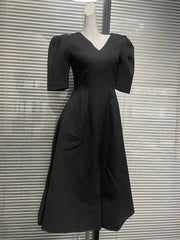 Three-quarter angle of the dress capturing the drape and volume through the skirt, styled simply for a formal, modern look.