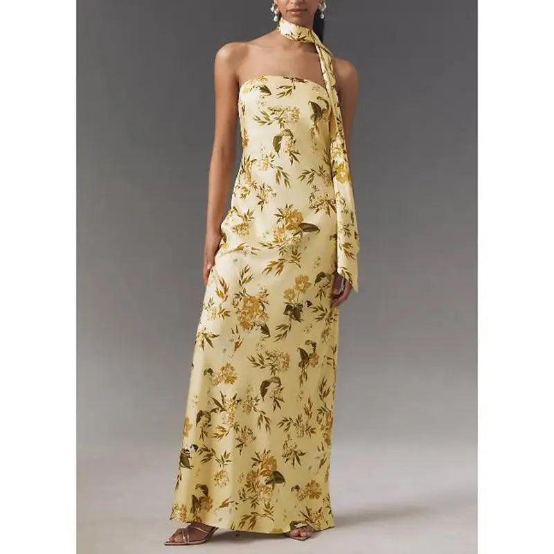 A woman wearing a  flowy long summer dress, worn with minimal sandals, with a plain background