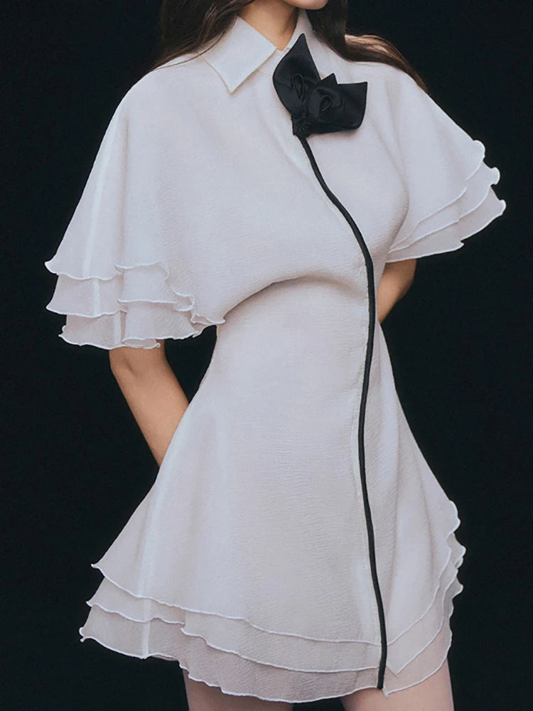 Flutter sleeve A-line dress with soft layered ruffles and black trim and bow on a black background