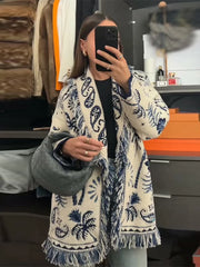 Detailed look at the fringe hem and knit texture, highlighting the patterned finish and movement at the lower edge.