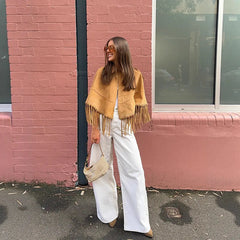 Close-up view of the turn-down collar and clean button closure on a draped cape-style coat with fringe trim.