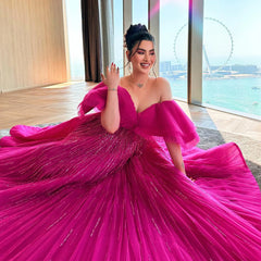 A woman modeling a fuchsia off-shoulder ball gown with a sweetheart neckline.