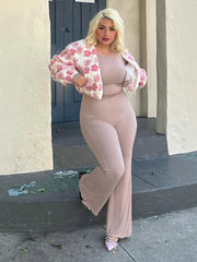 Woman in a pink floral jacket and matching pants standing on a sidewalk.