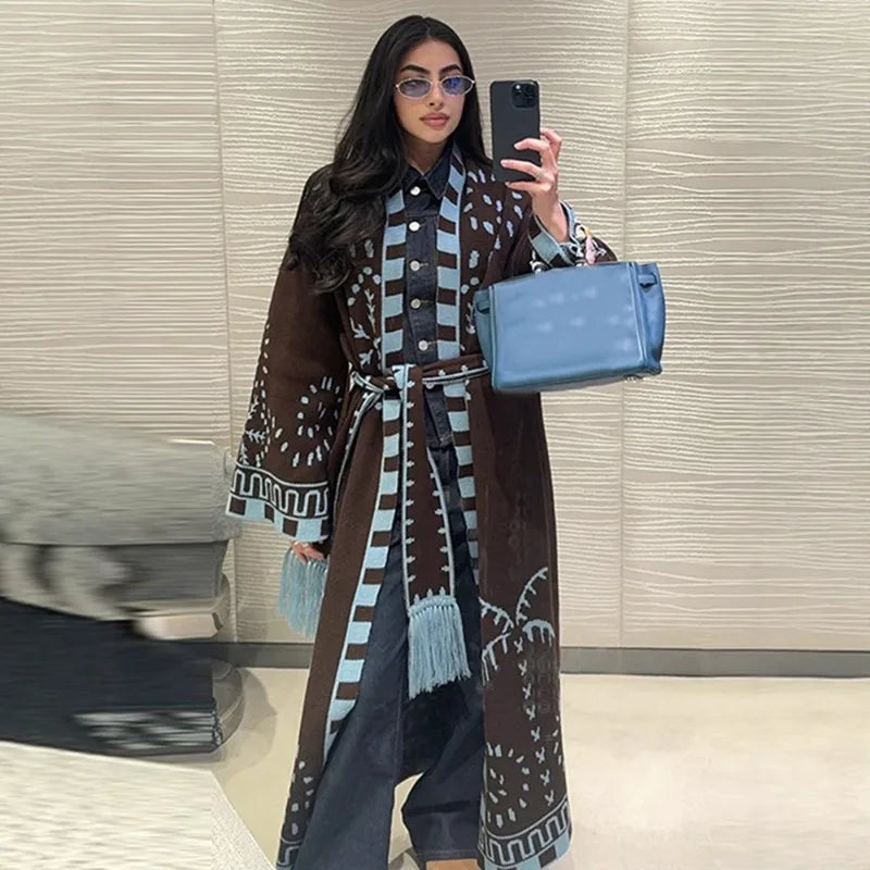 Mirror selfie showing a brown long knit cardigan with geometric pattern and tassel trim, belted at the waist over relaxed denim.