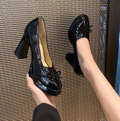 Glossy black dress shoes with butterfly bow detail