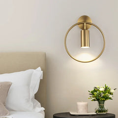 Gold circle wall sconce lighting up modern white wall