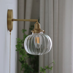  Lighted gold wall light mounted beside a curtain with a pull chain.