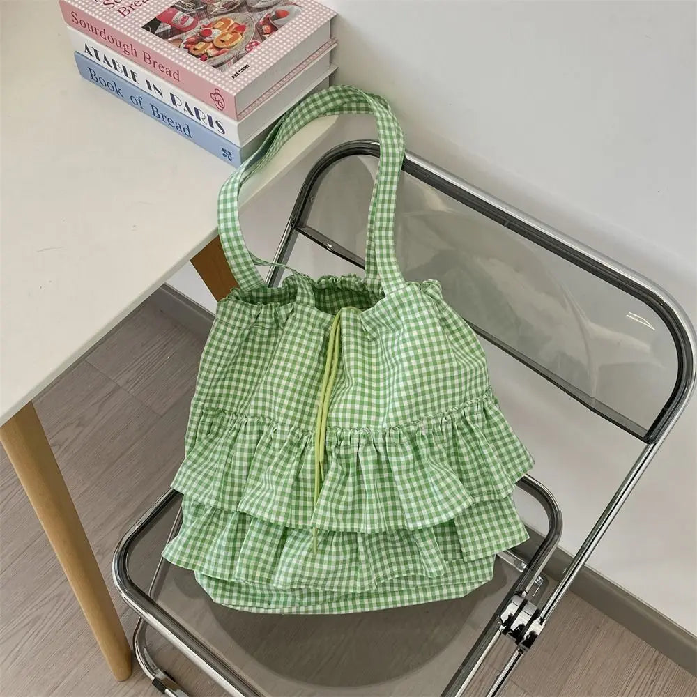 Green gingham ruffle shoulder bag on a chair with books
