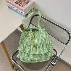 Green gingham ruffle shoulder bag on a chair with books