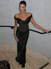 Woman in a black off-shoulder gown standing indoors.