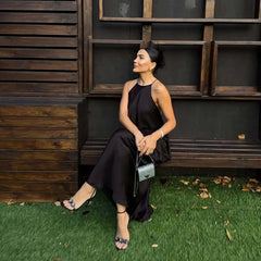 woman in a black halter backless maxi dress sitting on the bench