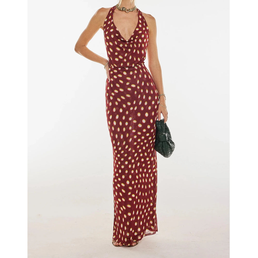 A woman modeling a halter backless floral print maxi dress.