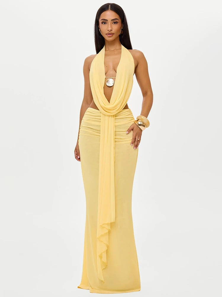 A woman wearing a yellow halter crop top and a matching maxi skirt set.