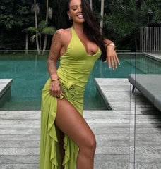 Women wearing a green halter neck maxi dress with a high split and floral detail, standing in front of a swimming pool.