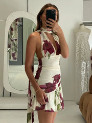 A woman is taking a mirror selfie wearing a dress in a room with a mirror and clothing items.