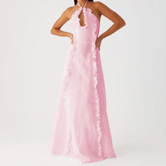 A woman modeling a black velvet halterneck maxi dress with a backless design.