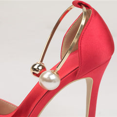 A  red high heels with pearl metal buckles and open-toe platforms close up view.
