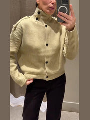 Model taking a mirror photo while wearing a high-neck knit cardigan styled casually with relaxed trousers