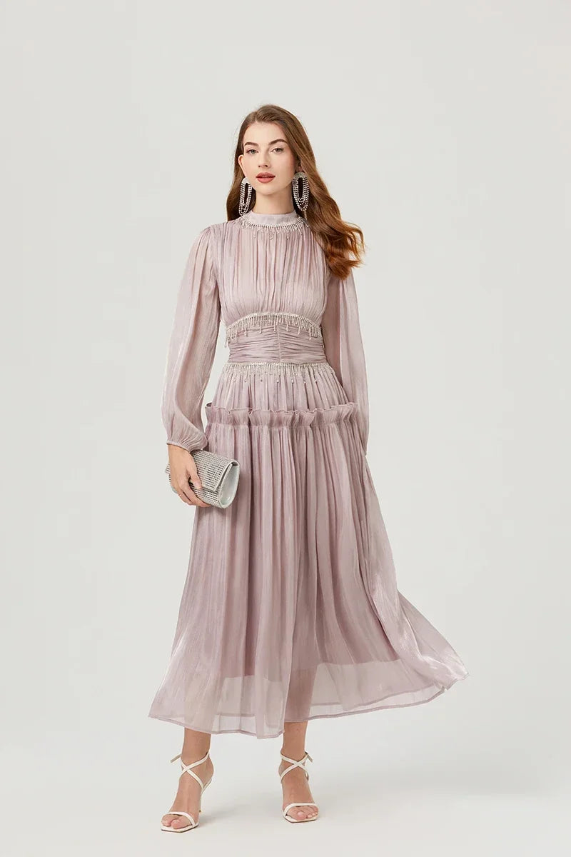 Model wearing a light silver chiffon midi dress with a high neckline and long lantern sleeves, holding the skirt to show movement.