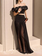 A woman wearing a black two-piece set with a sheer patchwork skirt and a short-sleeve top.