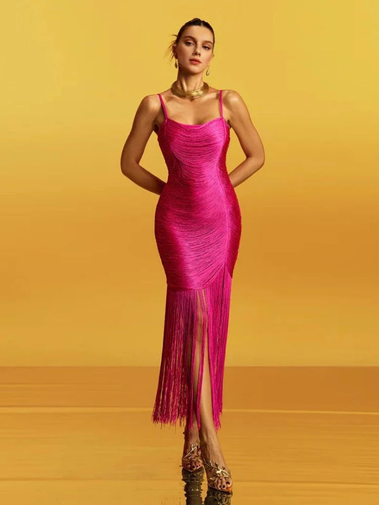 Bright pink spaghetti-strap midi dress on a yellow studio backdrop, showing a square neckline and sleek sheath fit through the body.