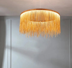 A gold and ivory tassel chain chandelier hanging in a room with a living space in the background.