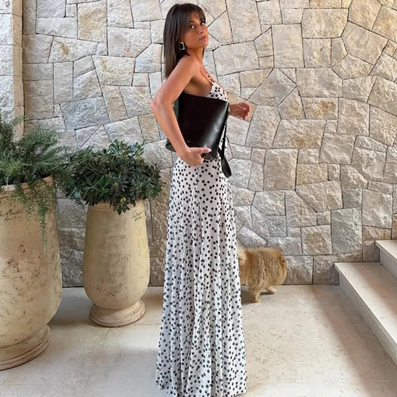 Woman in a junior A-line polka dot evening dress perfect for high street fashion holding a clutch in front of a stone wall.