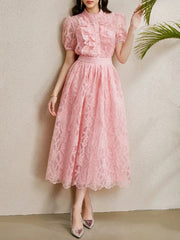 A woman modeling a lace midi dress with ruffles and a round neckline.