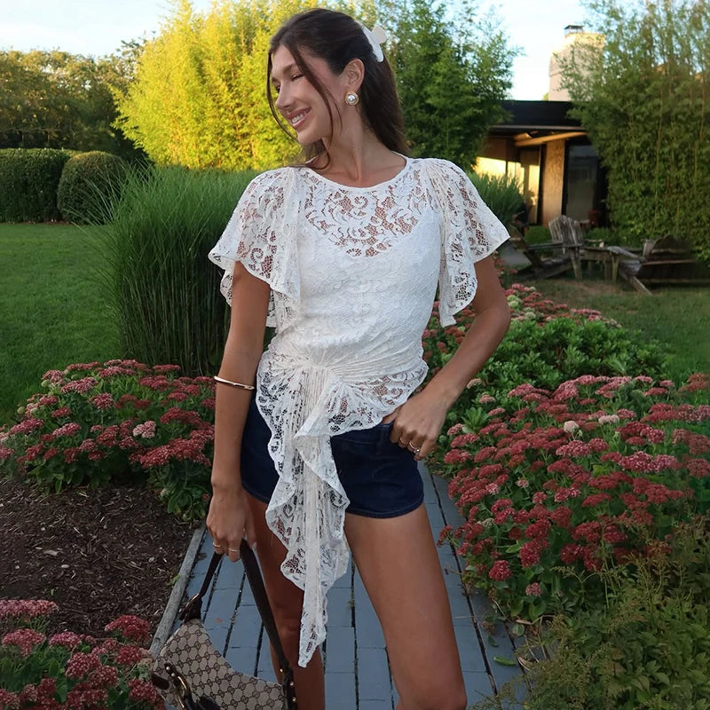 A woman wearing a lace splice irregular T-shirt with sheer ribbon sleeves.

