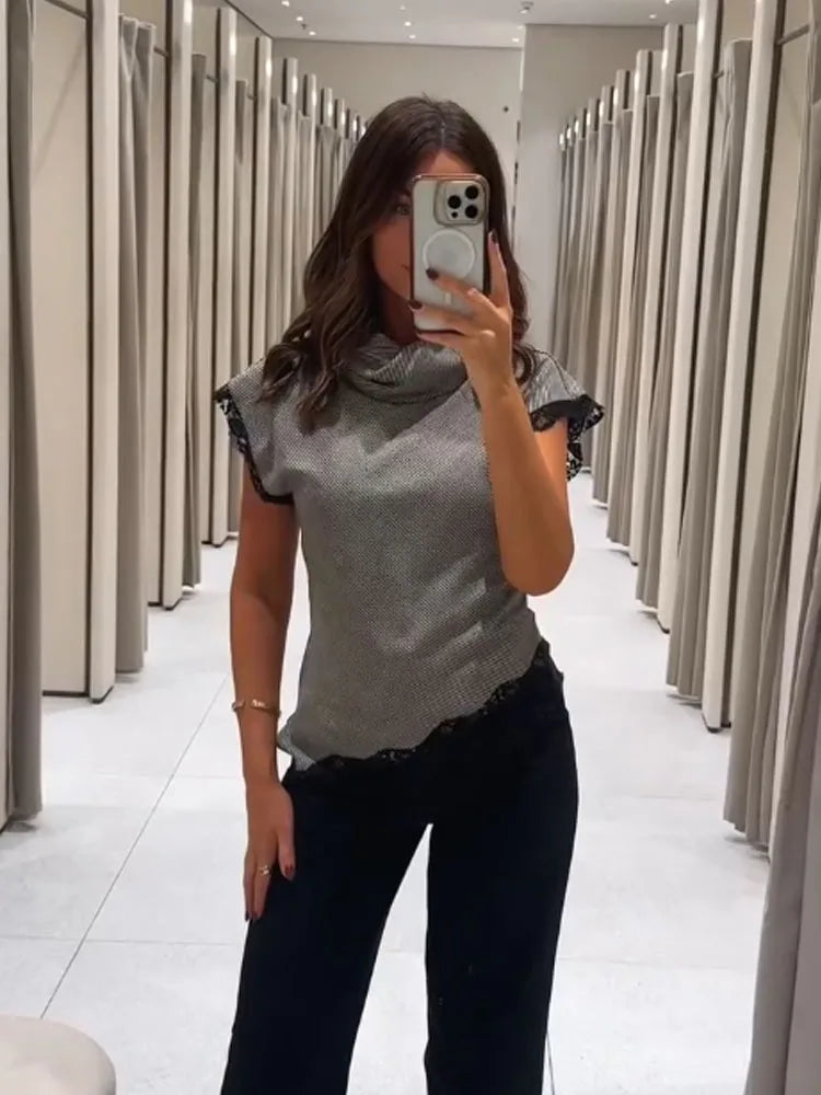 Mirror-selfie view of a sleeveless lace-trim stand collar top paired with tailored trousers in a contemporary fitting room.
