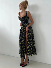 A woman wearing a lace-up neckline on a black floral maxi dress with a white background.