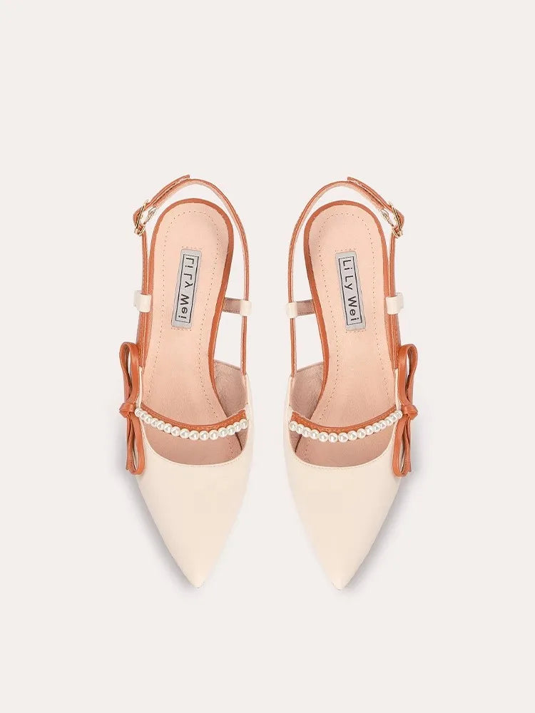 A pair of sandals with a thin heel, pearl beads, and a bow detail.