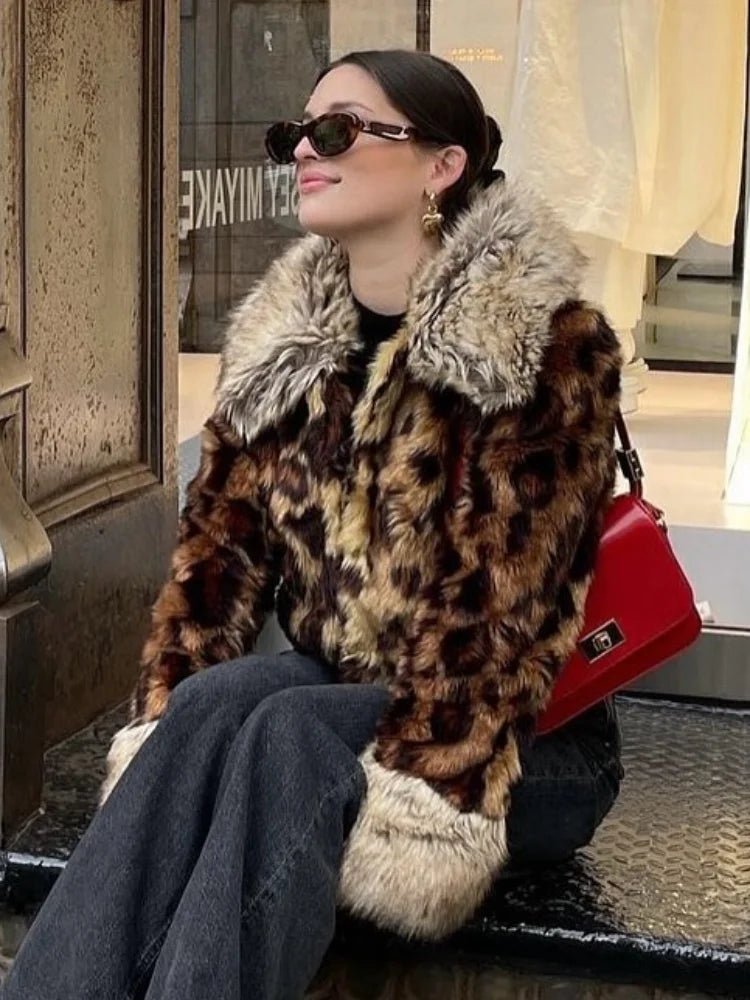 Woman wearing a leopard print coat with fur collar sitting on a bench.