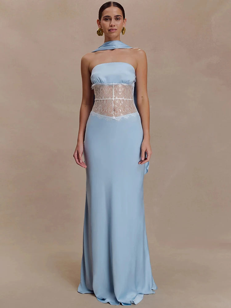 Model wearing a light blue strapless maxi dress with a scarf-style neck detail and sheer lace waist panel against a warm beige backdrop.